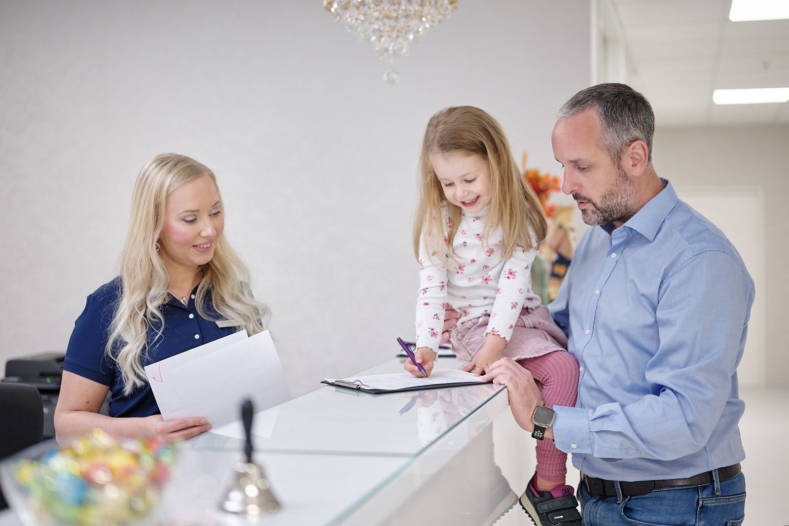 Familie bei der Anmeldung am Empfang der Hausarztpraxis Chur West